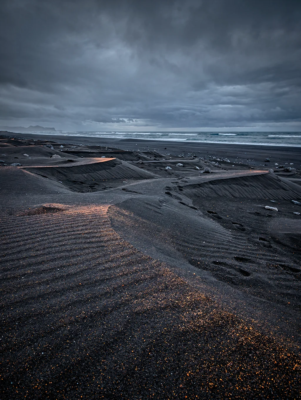 Black volcanic sand with glowing glacial ice at twilight